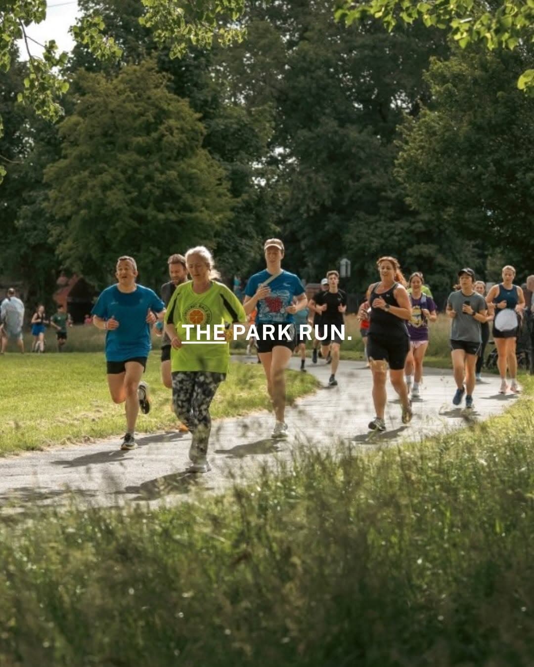 Runners and walkers gathered at a parkrun event on a Saturday morning, with participants of various ages and abilities on a tree-lined path
